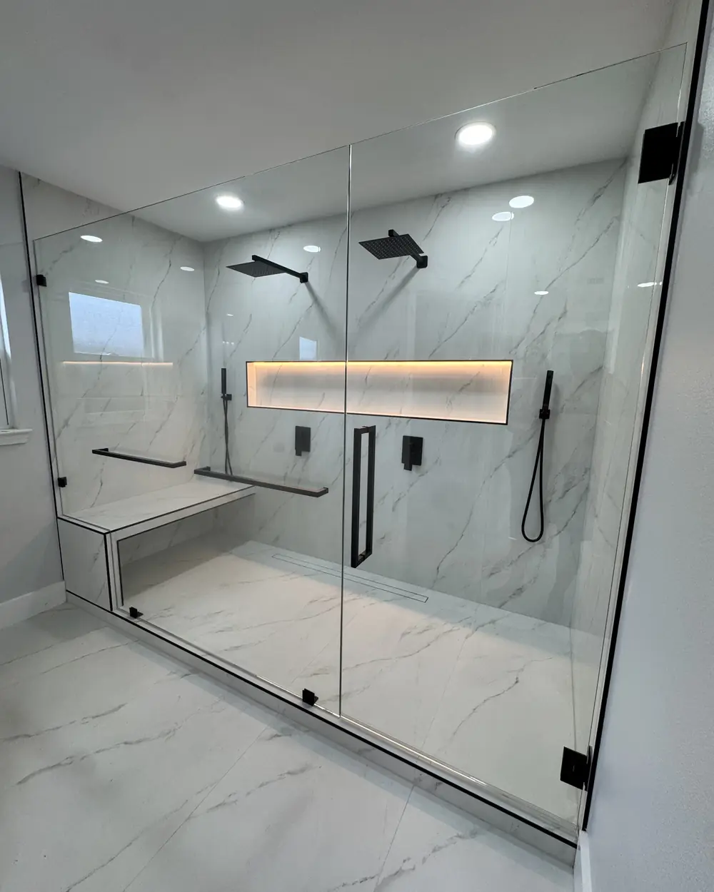 Walk-in shower with a lit wall niche and built-in bench